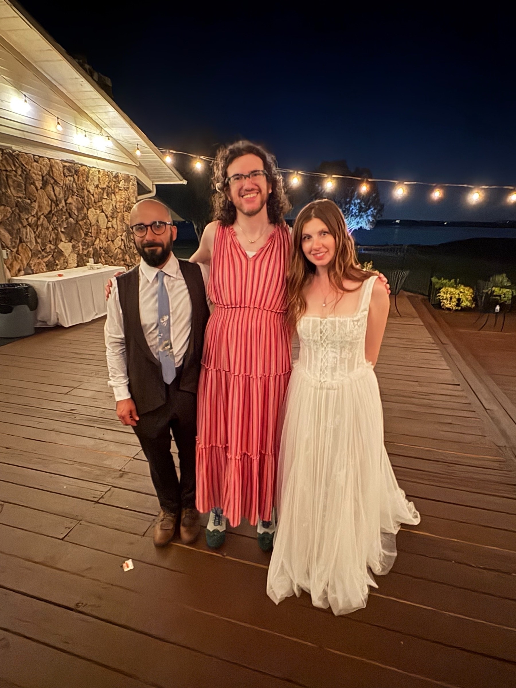 Me in a summer dress flanked by a bride & groom.